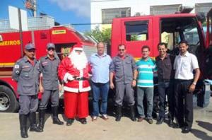 O presidente da ACETO, Ricardo da Emex, ao lado do Papai Noel, dos homens do Corpo de Bombeiros (parceiros no projeto) e da equipe da Associação Comercial da cidade