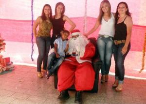 O Papai Noel posa com criança na Praça Tiradentes rodeado pelas colaboradoras da ACETO